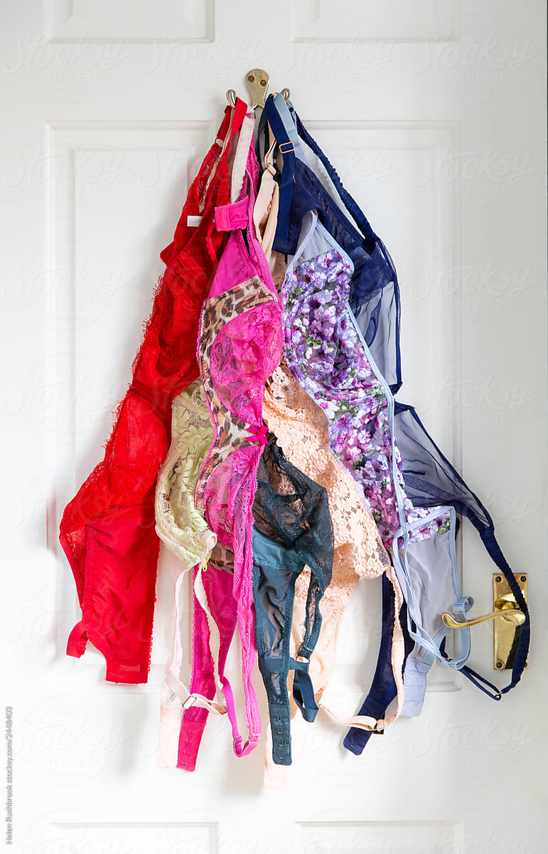 A rainbow of bras hanging on a door.