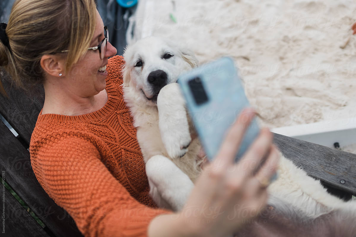 woman holding puppy as she takes a selfie