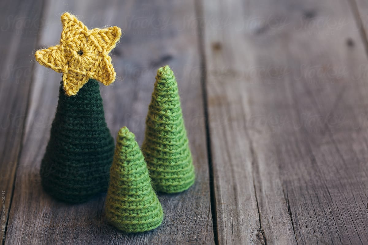 Three little crocheted christmas trees on a wooden background