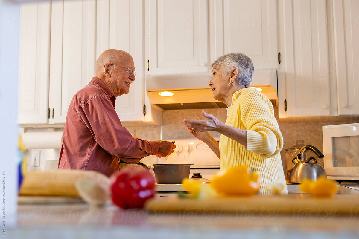 Happy Senior Citizen couple at home cooking dinner and talk