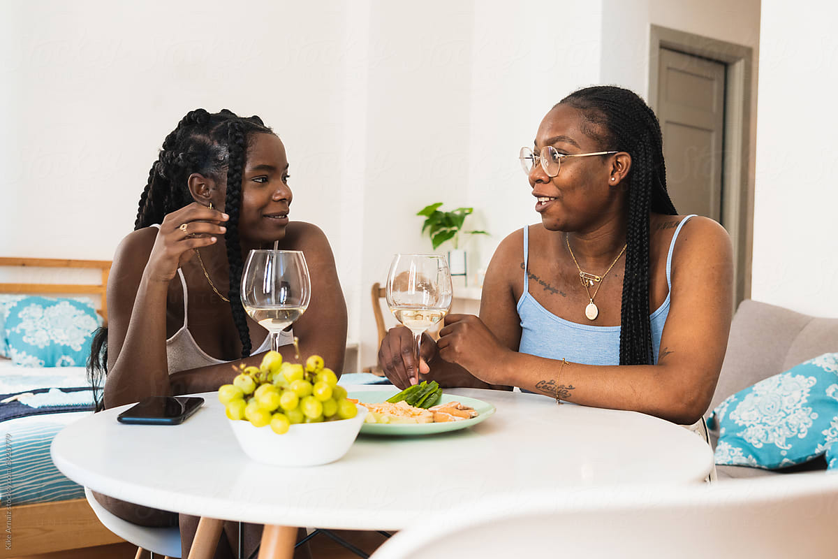 Relaxed girlfriends having wine with snacks at home