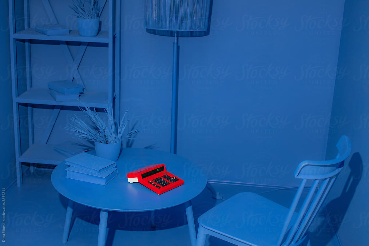 A red vintage calculator in an entirely monochrome blue room