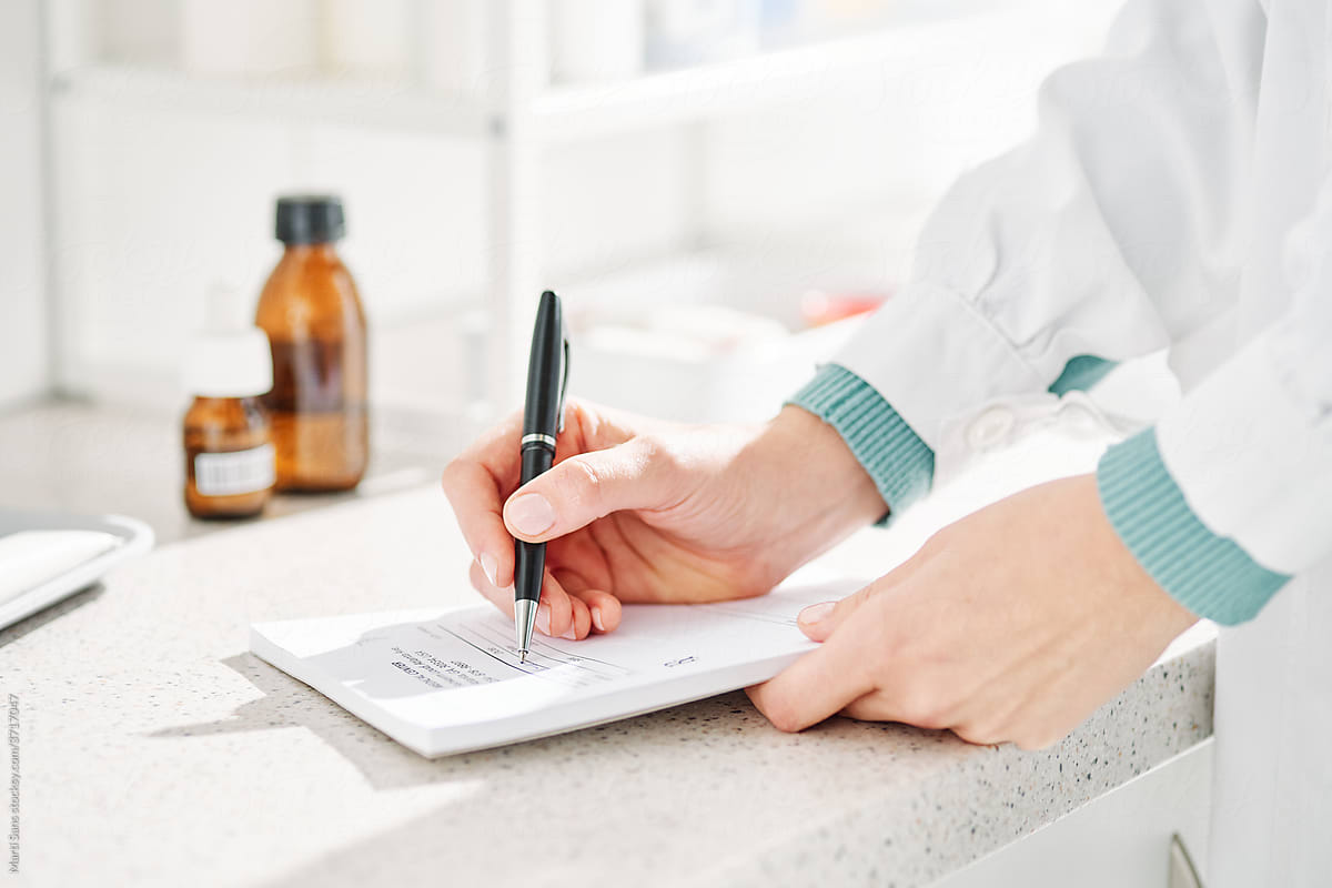 Unrecognizable doctor taking notes on paper in clinic