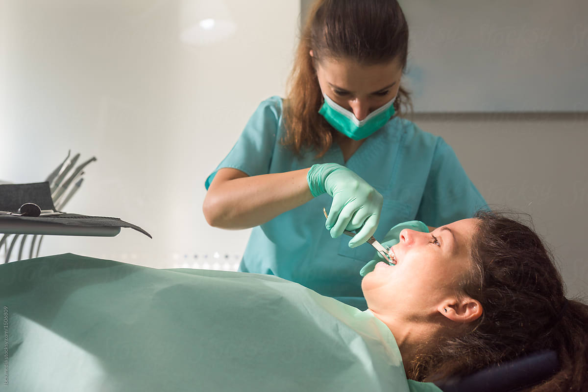 Female orthodontist fixing dental braces using orthodontic pliers