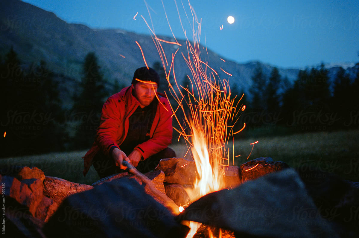 Man Crouching By Campfire At Night