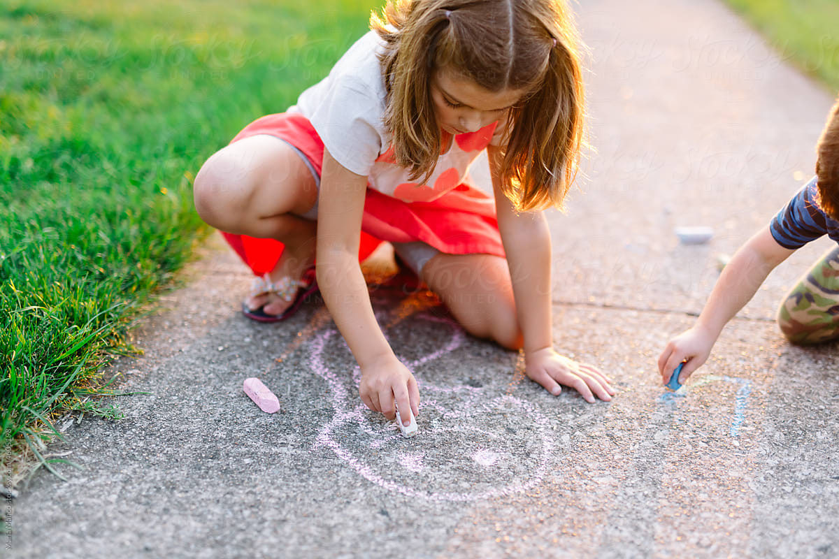 girl coloring with chalk on sidewalk