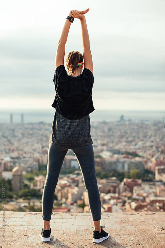 Fit woman doing stretching exercises above city in the morning.