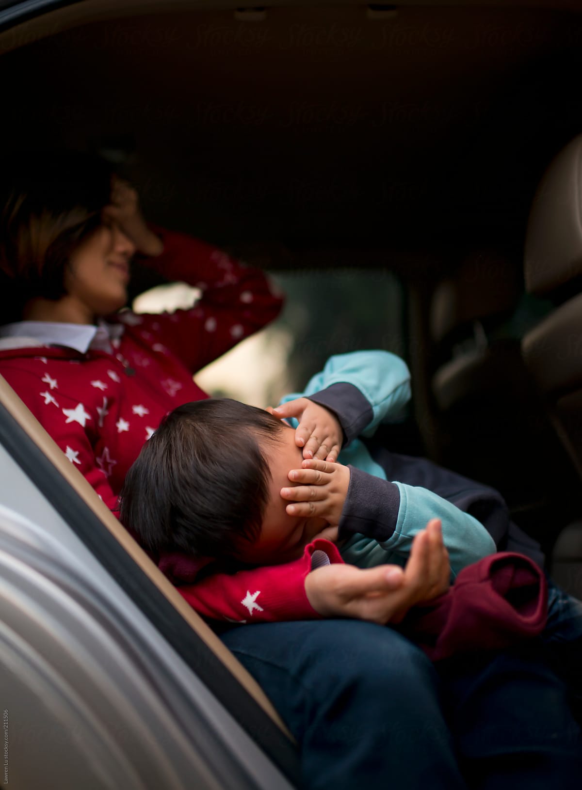 Mother resting and kid covering eyes in car