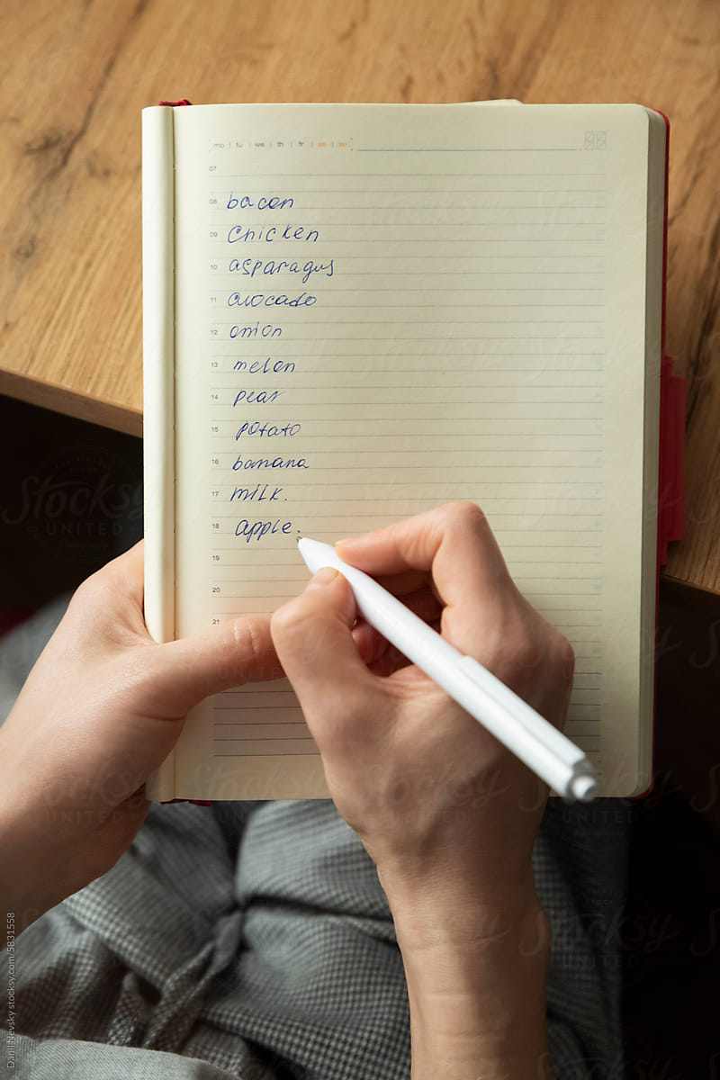 Crop woman making list in notebook