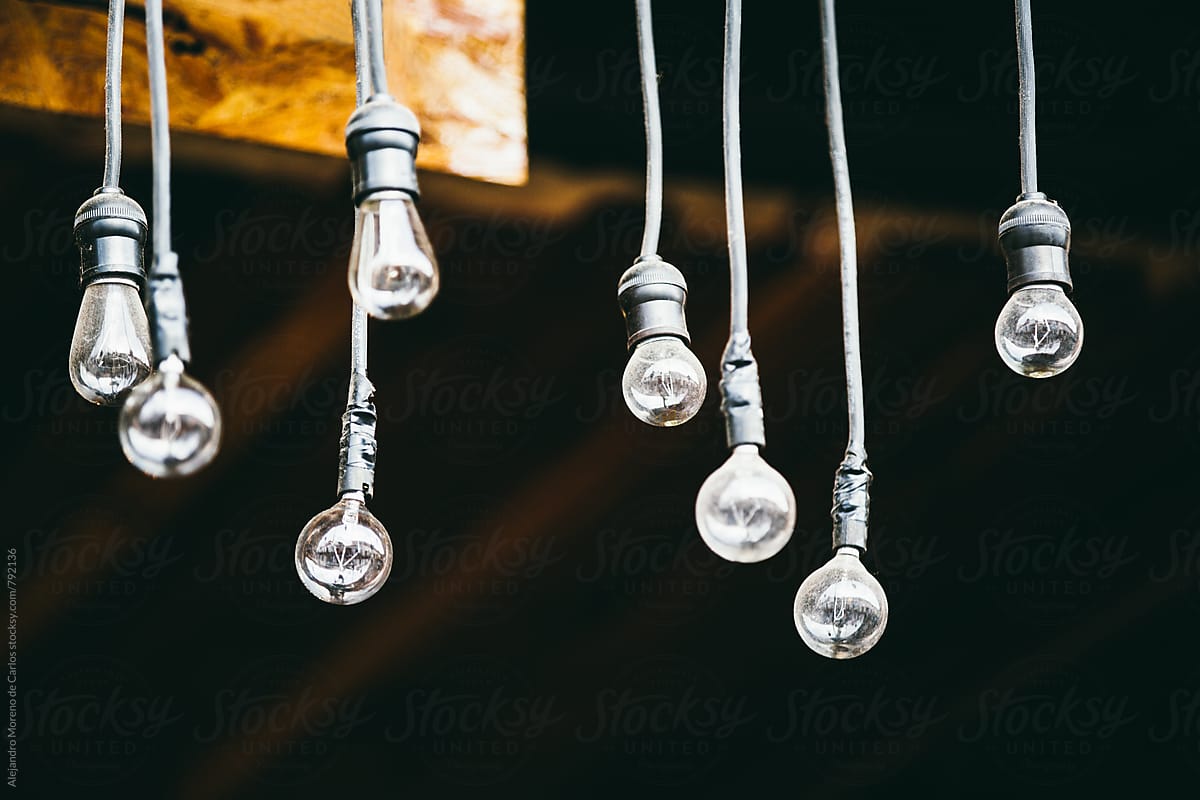 Exterior view of various lightbulbs hanging down with a wire from the ceiling with a dark background