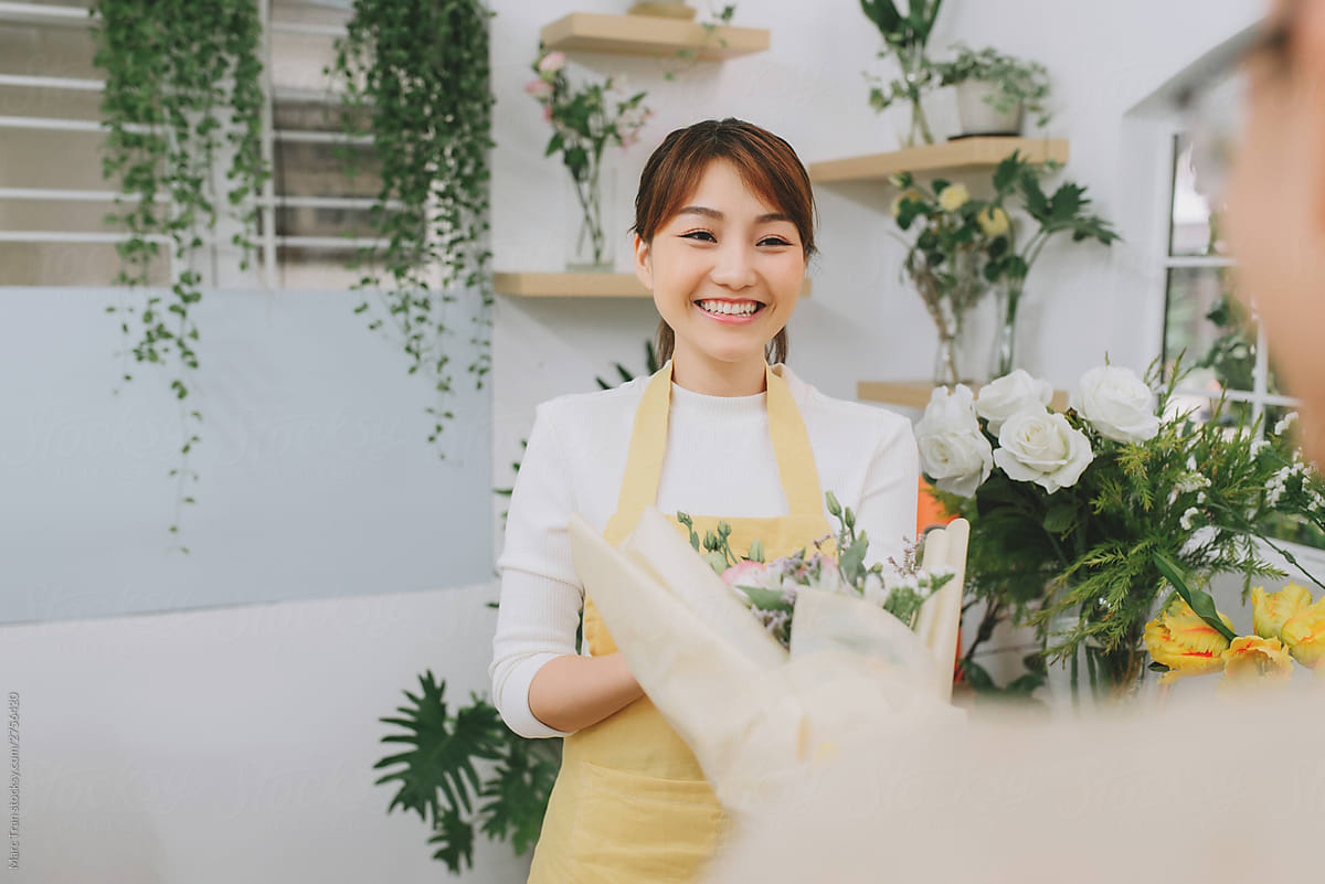 Portrait of female asian florist offering flowers