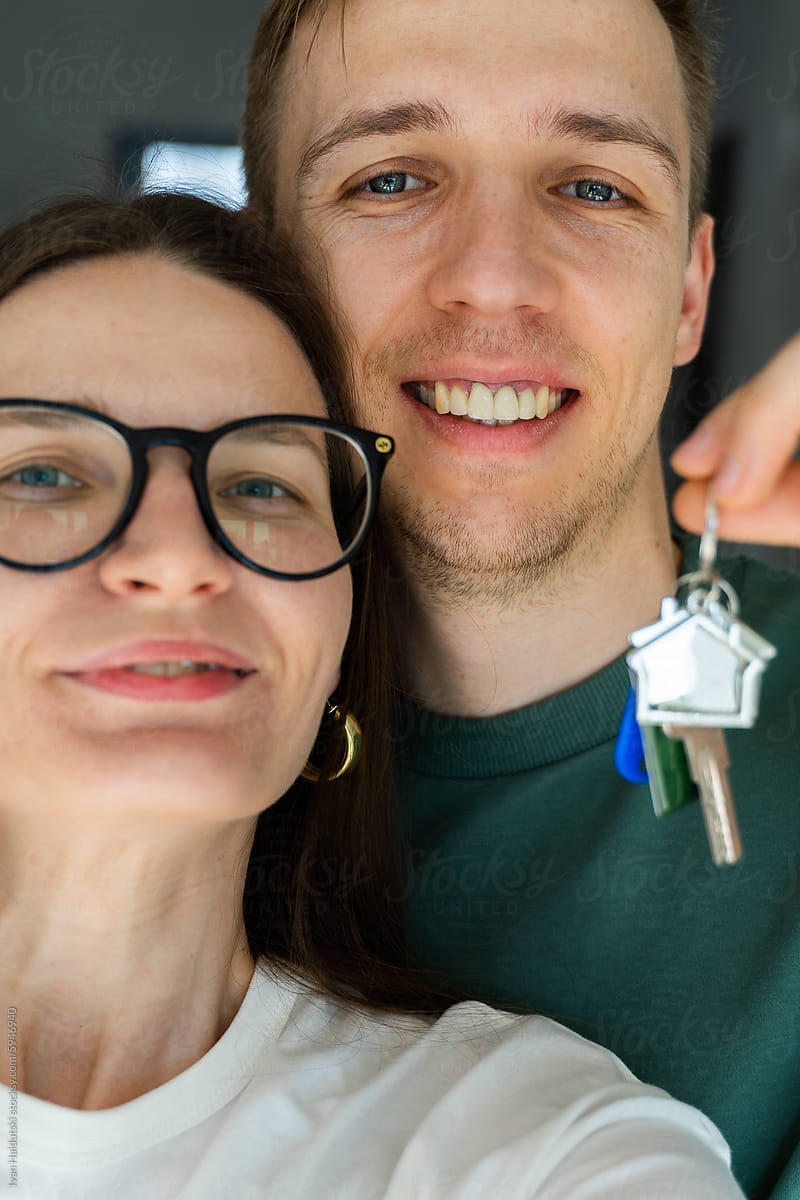Happy millennial couple selfie holding key from a new home/apartment