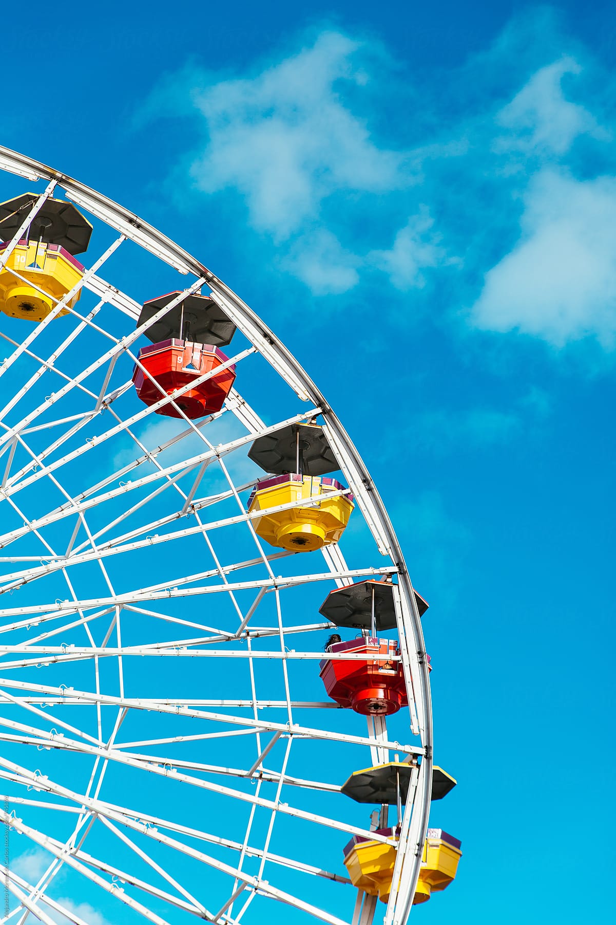 Detail of colourful ferris wheel against blue sky. Vertical