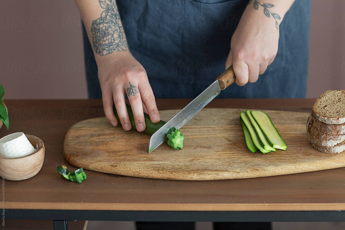 Woman Slicing Fresh Zucchini On Wooden Cutting Board