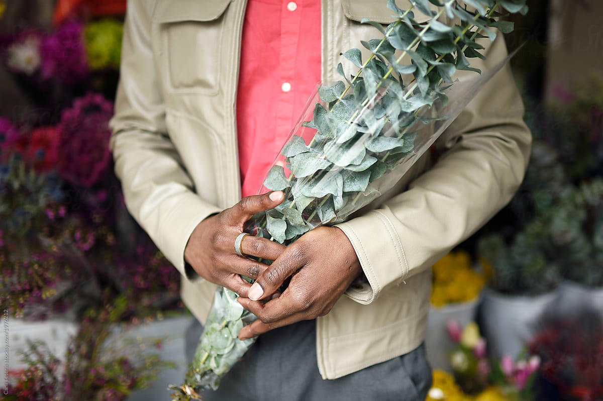Man shopping for greenery at a flower stall in a farmer\'s market