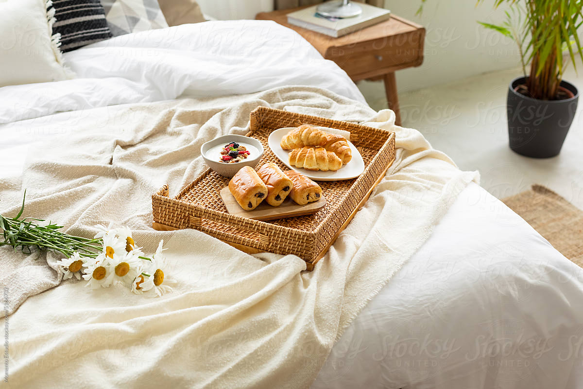 delicious breakfast of pastries on the bed with some flowers