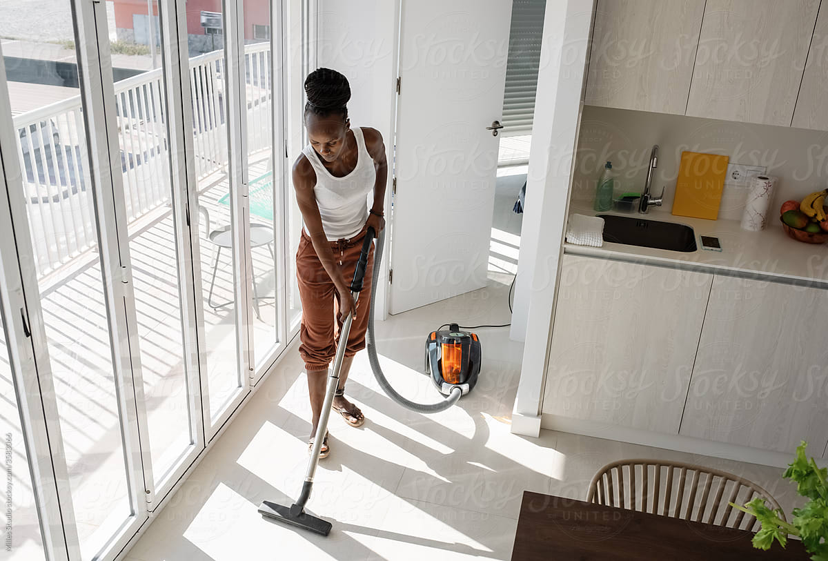 African woman cleaning floor near kitchen