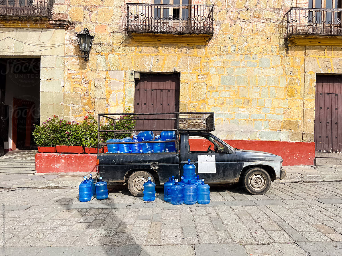 A pickup truck parked on the street full of blue water containers
