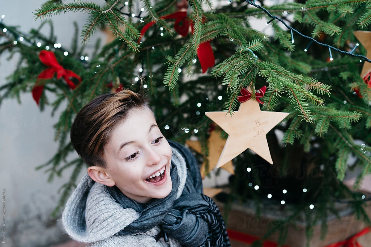 Boy by a decorated Christmas tree saying hello to someone