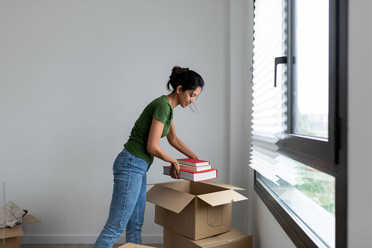 Young woman unpacking a moving box with books