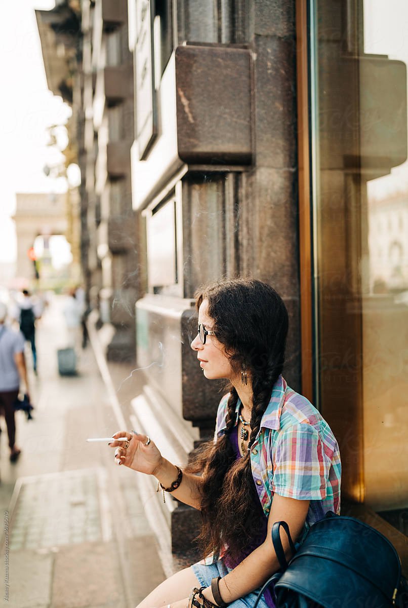 Portrait Of  Young Woman With Round Sunglasses smoking on the street