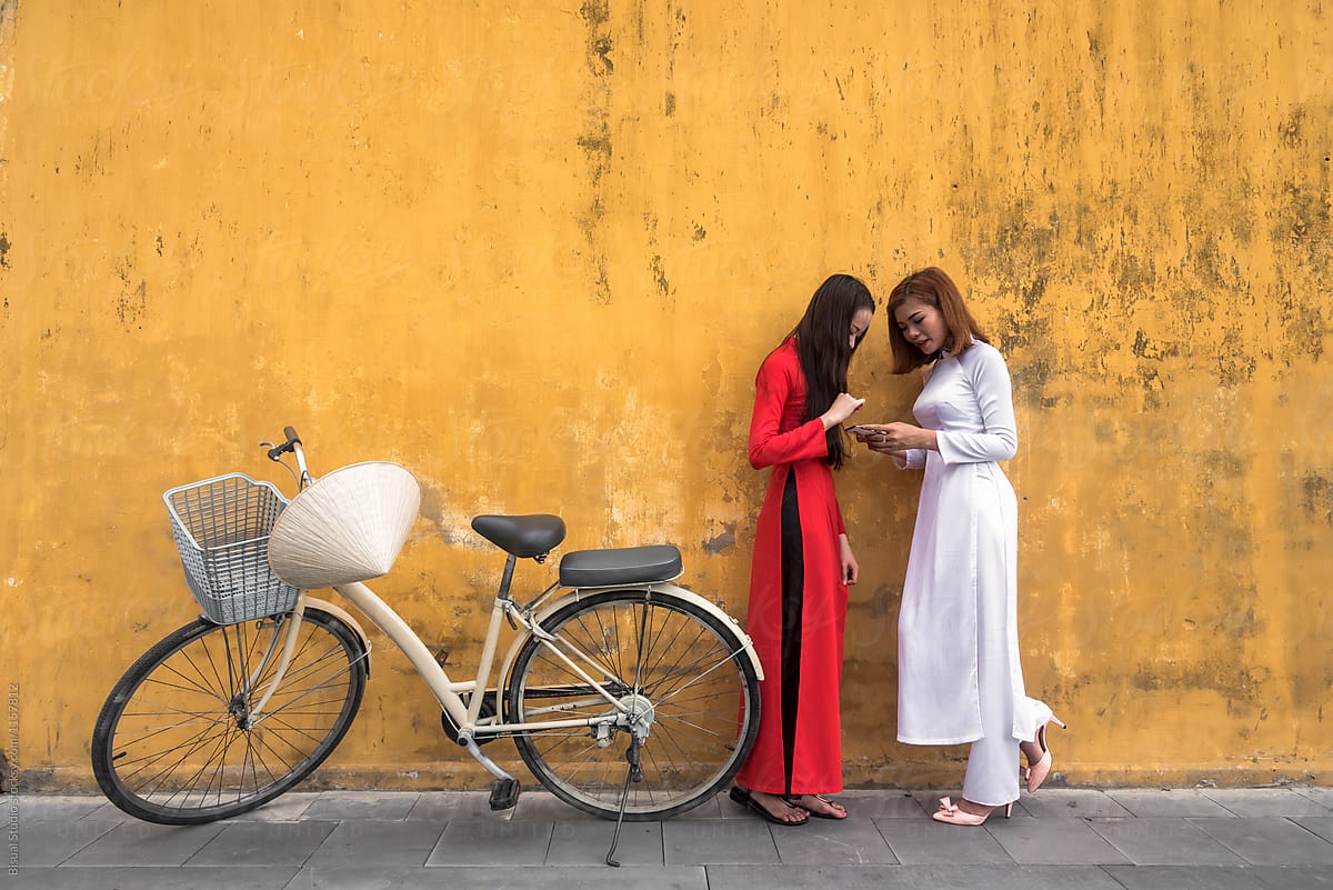 Asian women using phone in the street with bicycle parked over yellow background