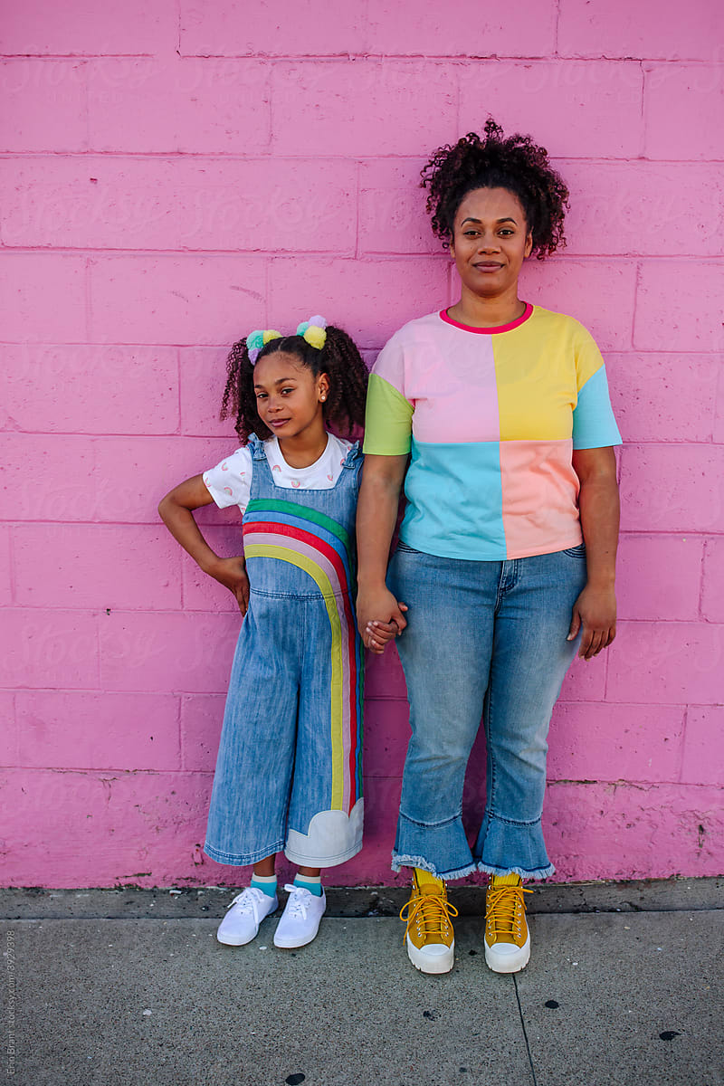 Mom and girl standing against pink wall