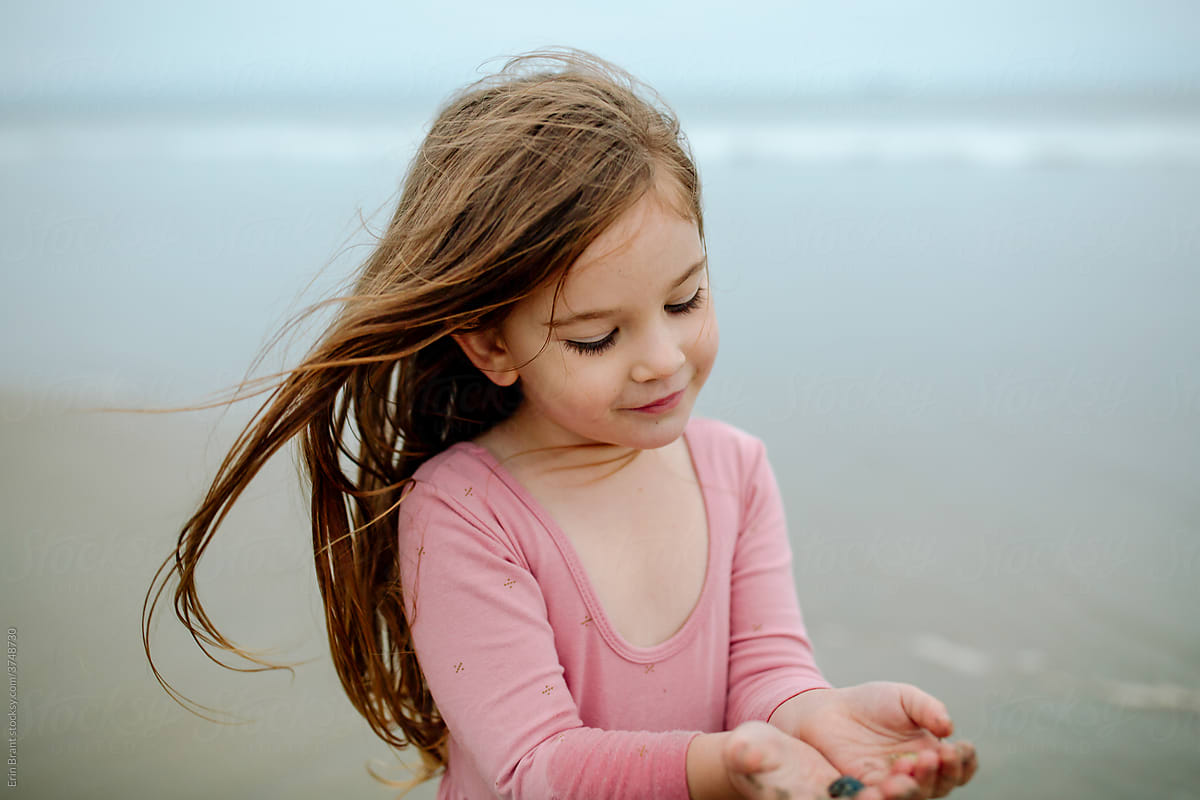 Young girl in pink dress holding seashells