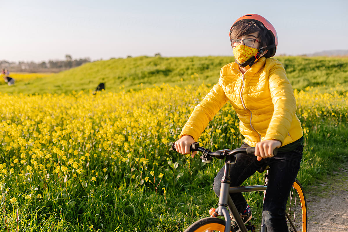 Teen boy riding bike along blooming field