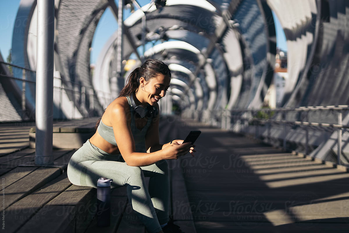 Athlete woman resting from her training using smartphone