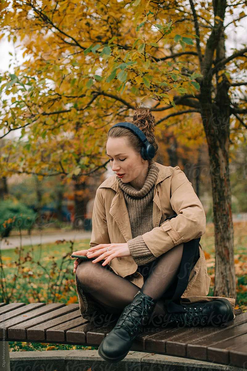 Woman on a bench using headphones