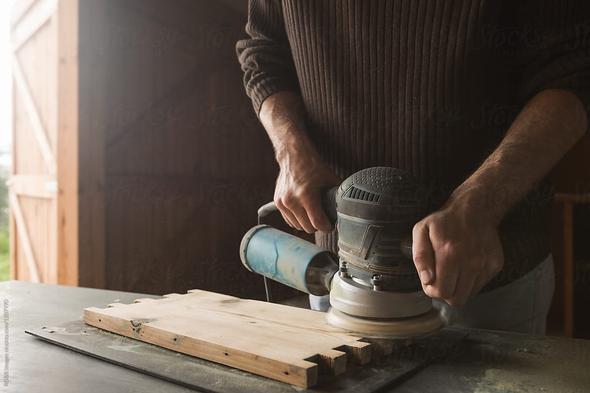 Carpenter polishing wood plank