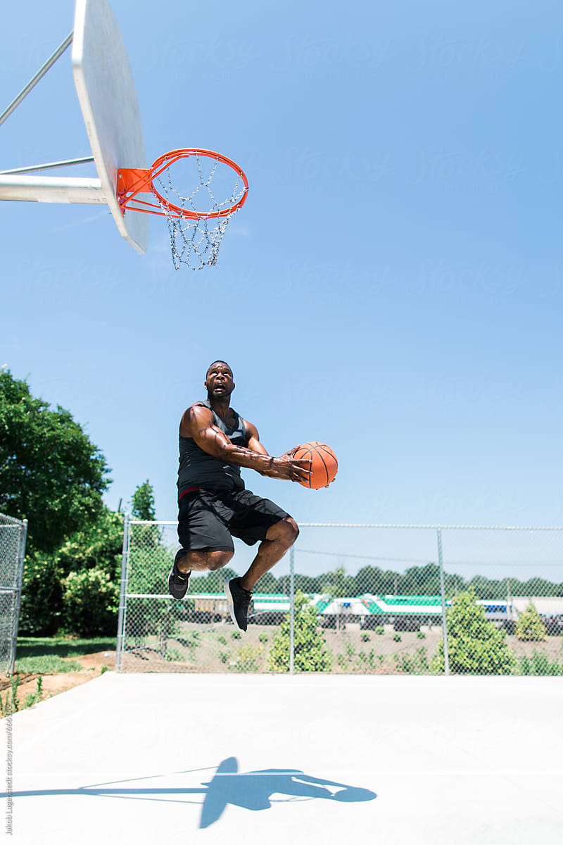 Athletic African-American man playing basketball outside