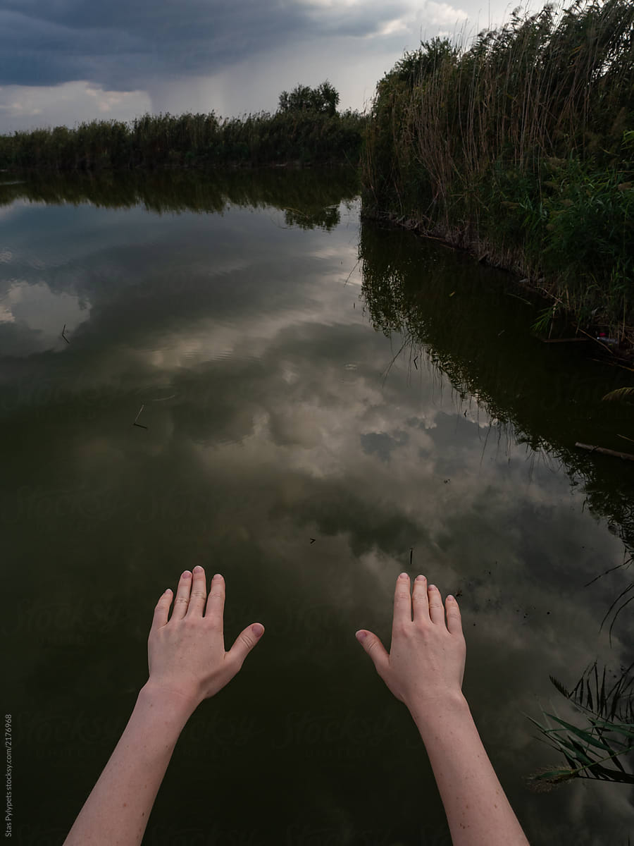 Hands against the sky and the lake