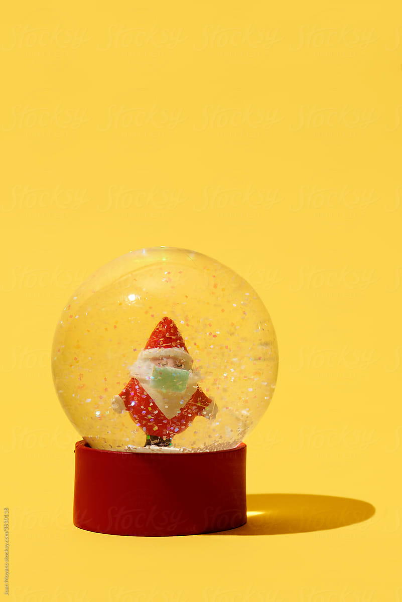 santa claus wearing a face mask in a snow globe
