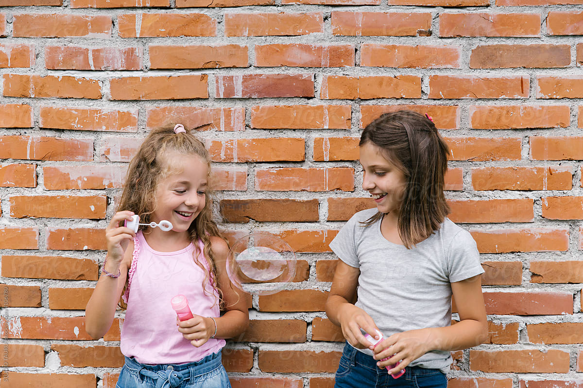 Two happy girls blowing soap bubbles