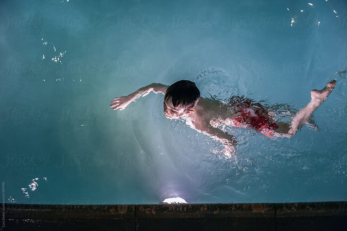 Boy swimming in a pool at night
