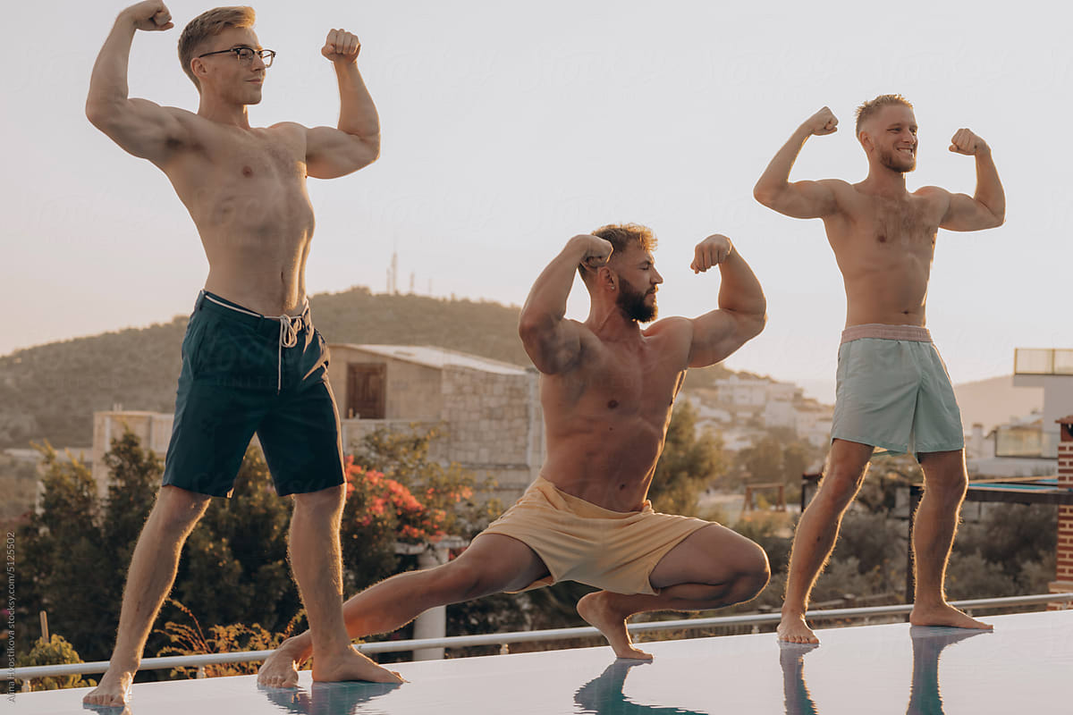 Athletic men showing biceps at poolside