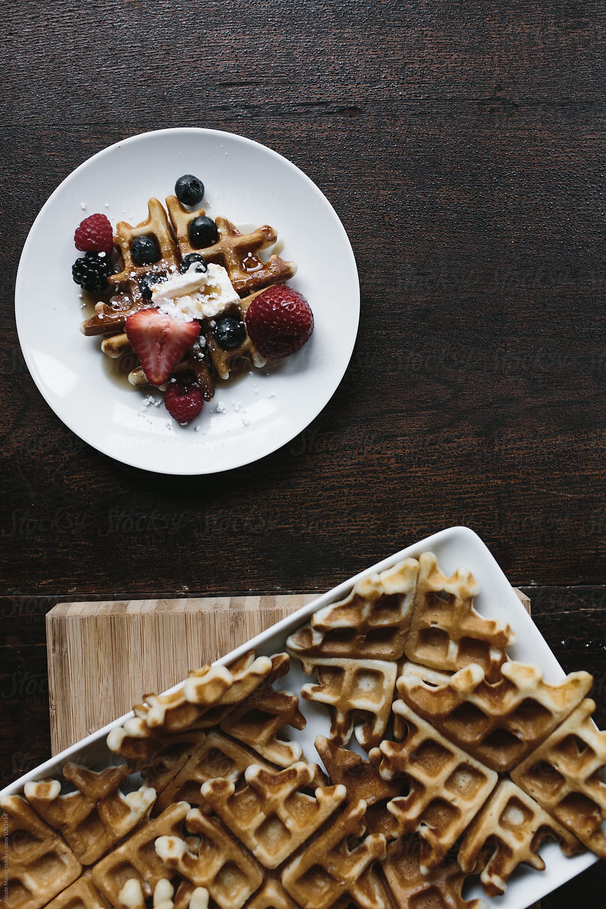 tray of waffles beside plate of waffle and berries