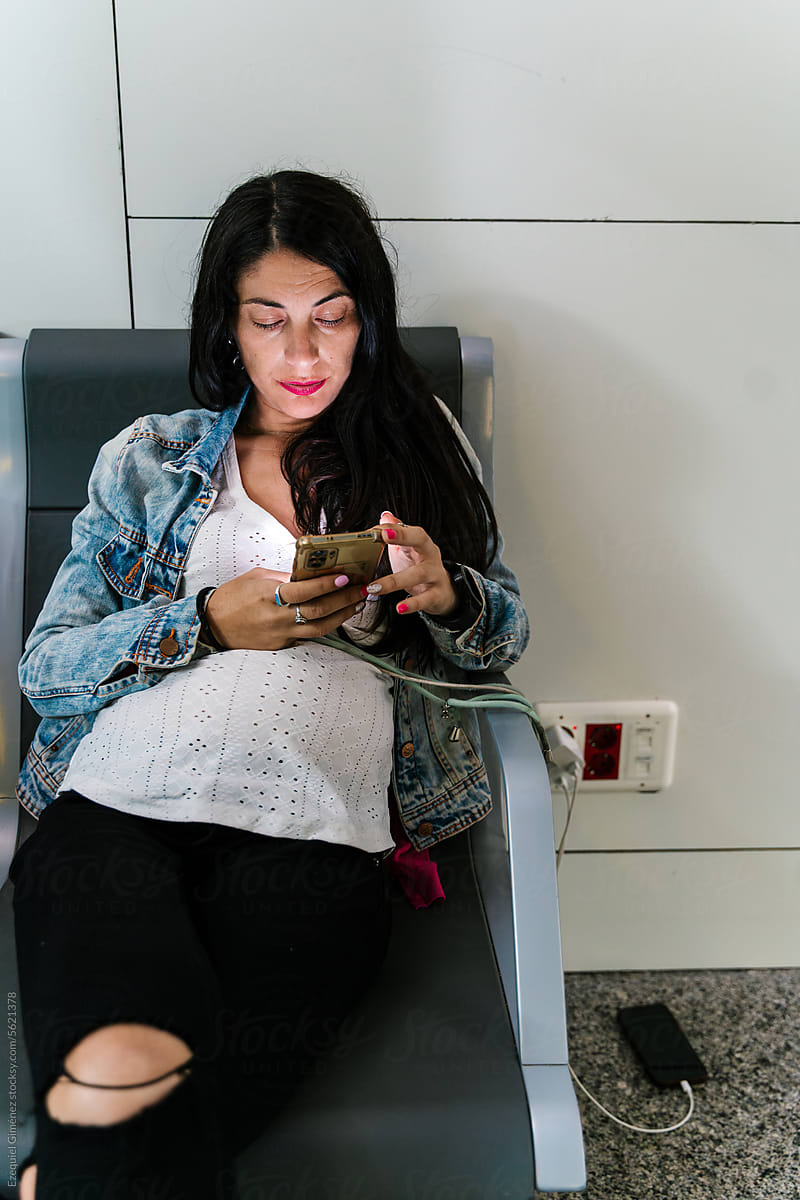 Pregnant woman with phone in waiting area