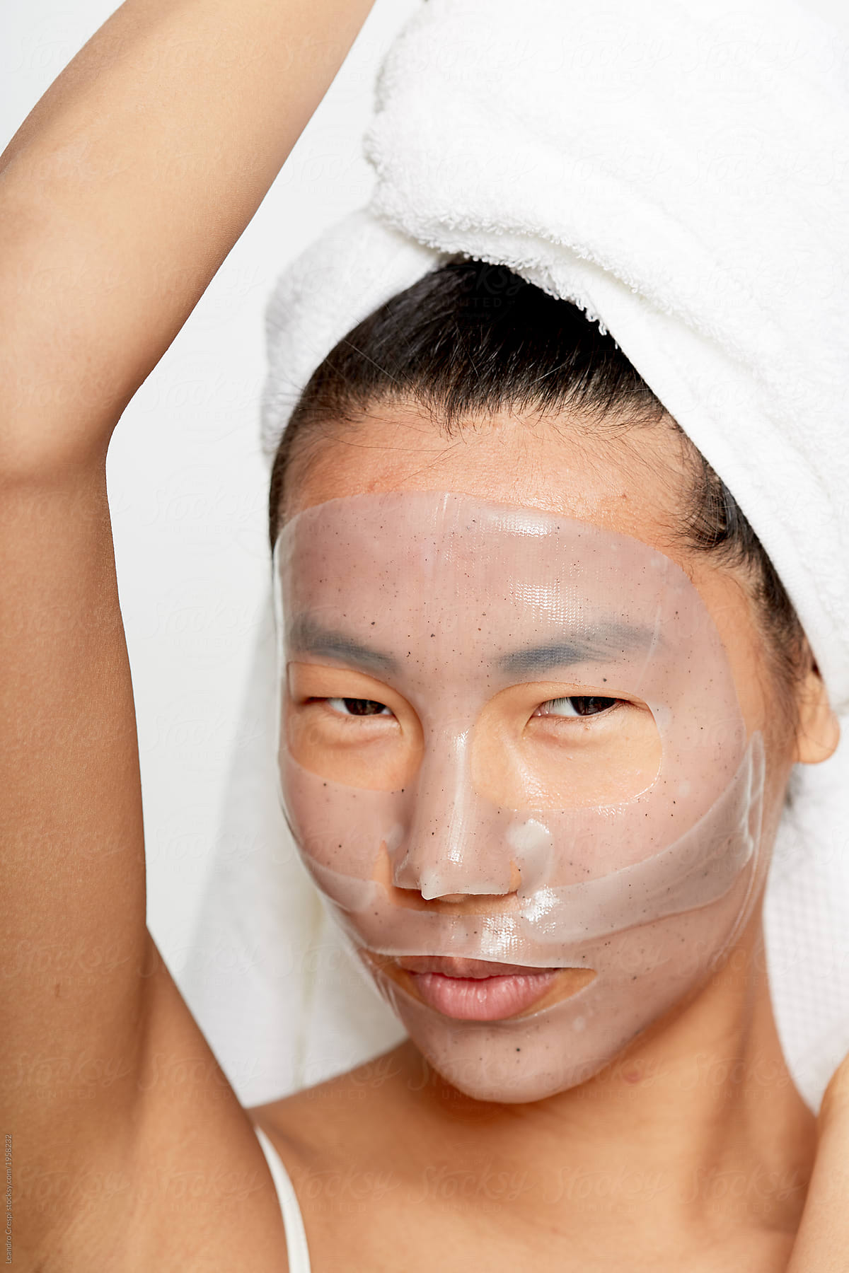 Smiling young asian woman enjoying facial gel mask