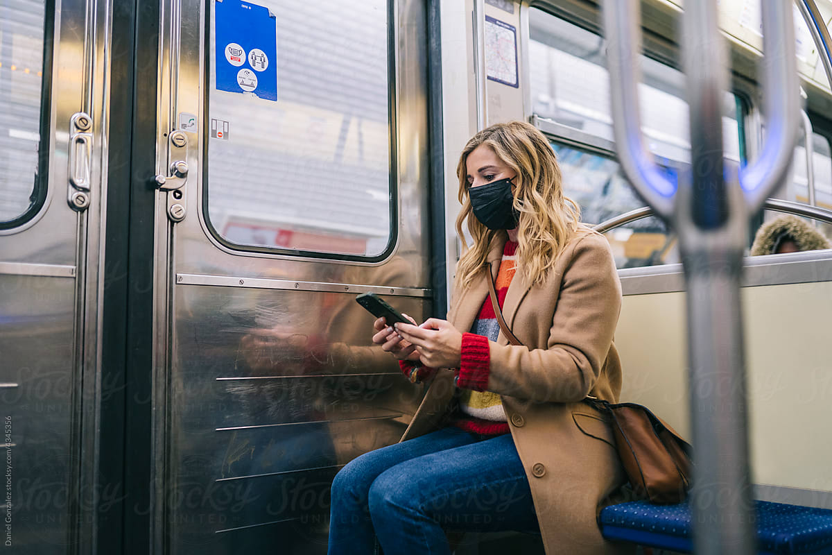 A woman with a mask in public transport with phone