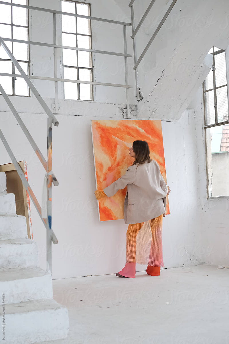 Female Artist Hanging Her Painting on Wall