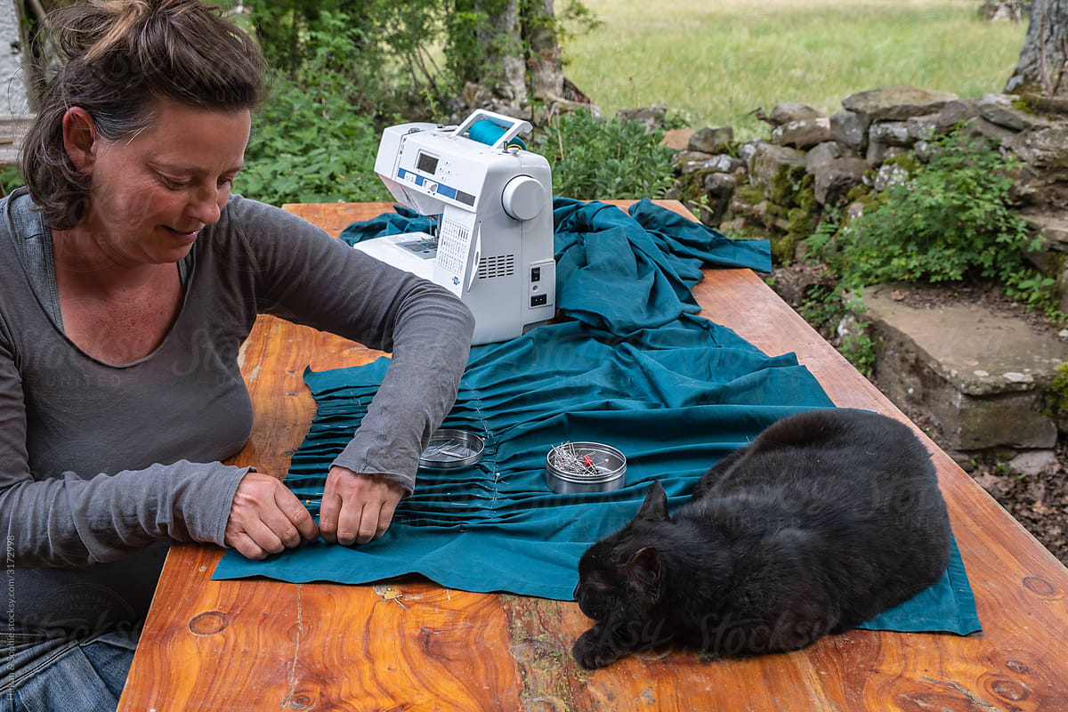 woman sewing with her cat close by