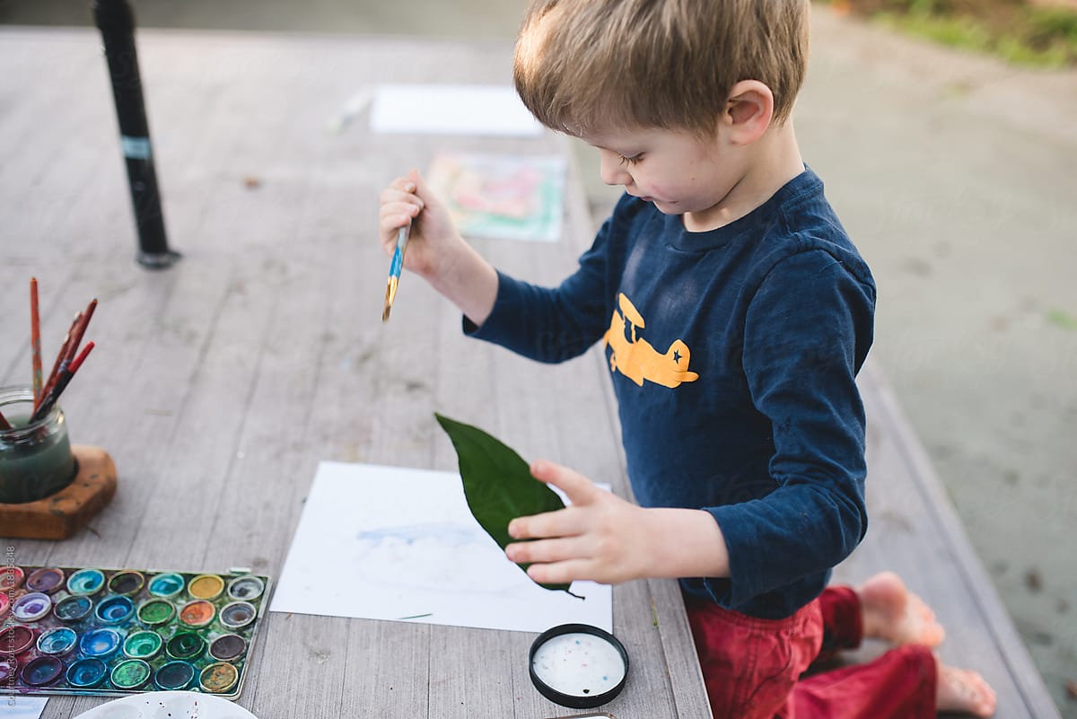 A boy studying and painting a leaf
