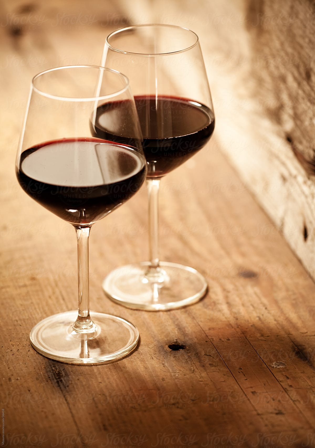 Glasses Of Red Wine On A Wooden Table." by Stocksy Contributor "Mosuno" - Stocksy