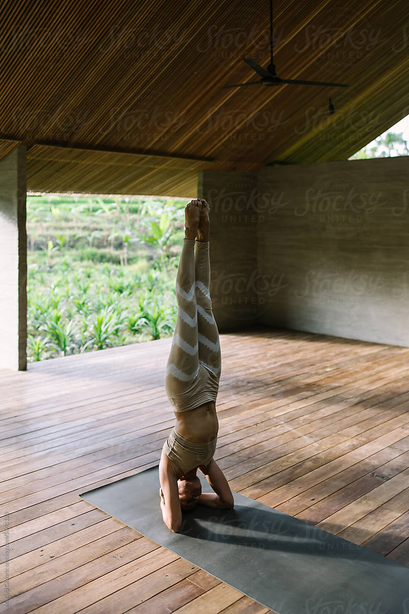 Adult yogi woman doing handstand in yoga studio