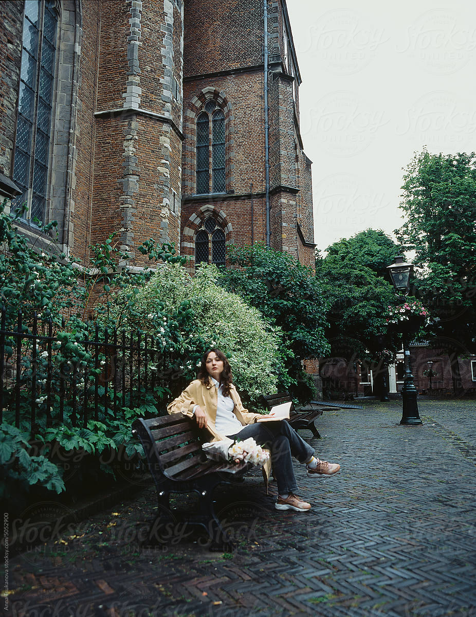 Woman sitting under the rain on the bench and reading book