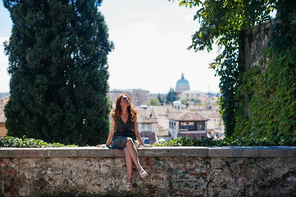 Mid Adult Woman Sitting on a Wall With Italian City View