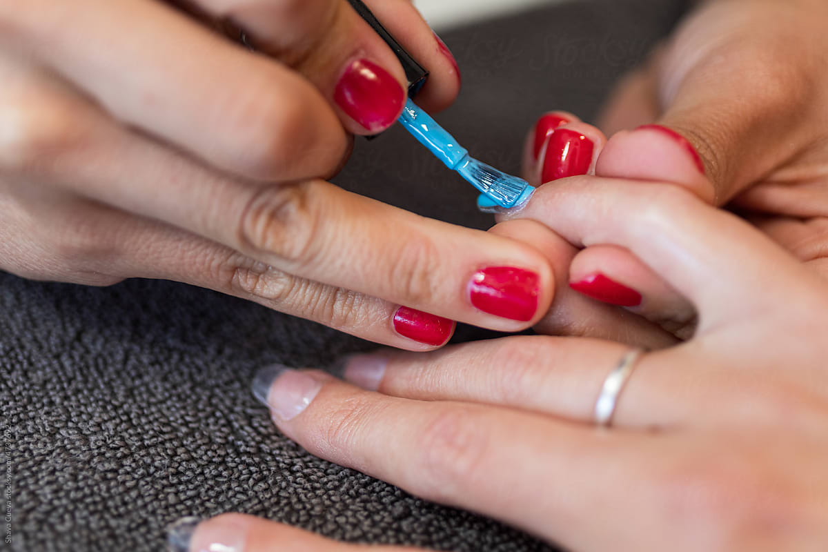 Closeup of a woman having her nails blue polished
